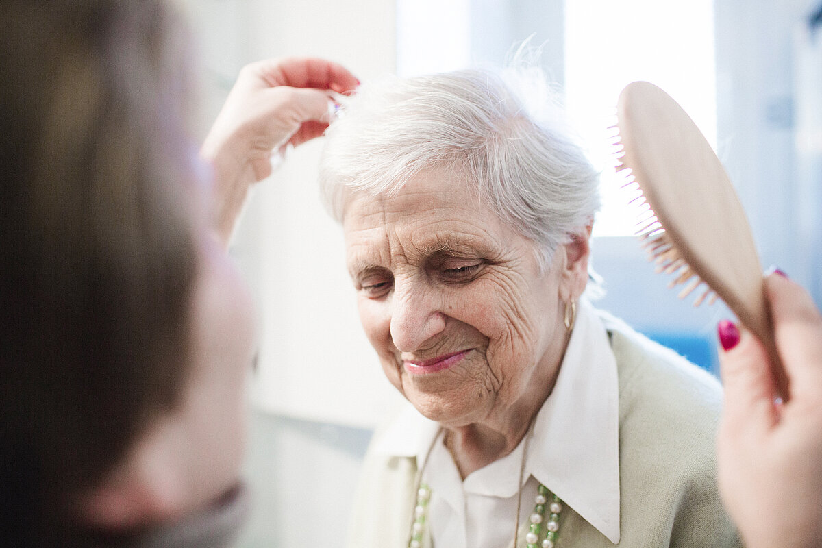 Seniorin bekommt die Haare gekämmt