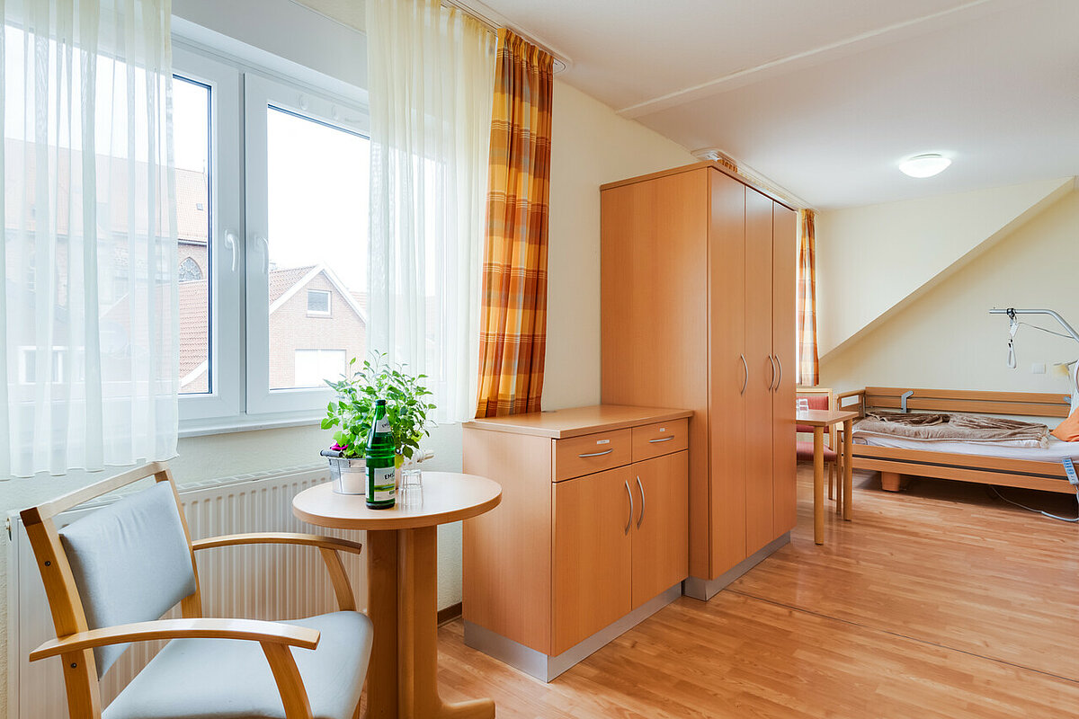 Einzelzimmer mit Kleiderschrank, Kommode, Bett und Sitzecke im Pflegeheim in Haselünne