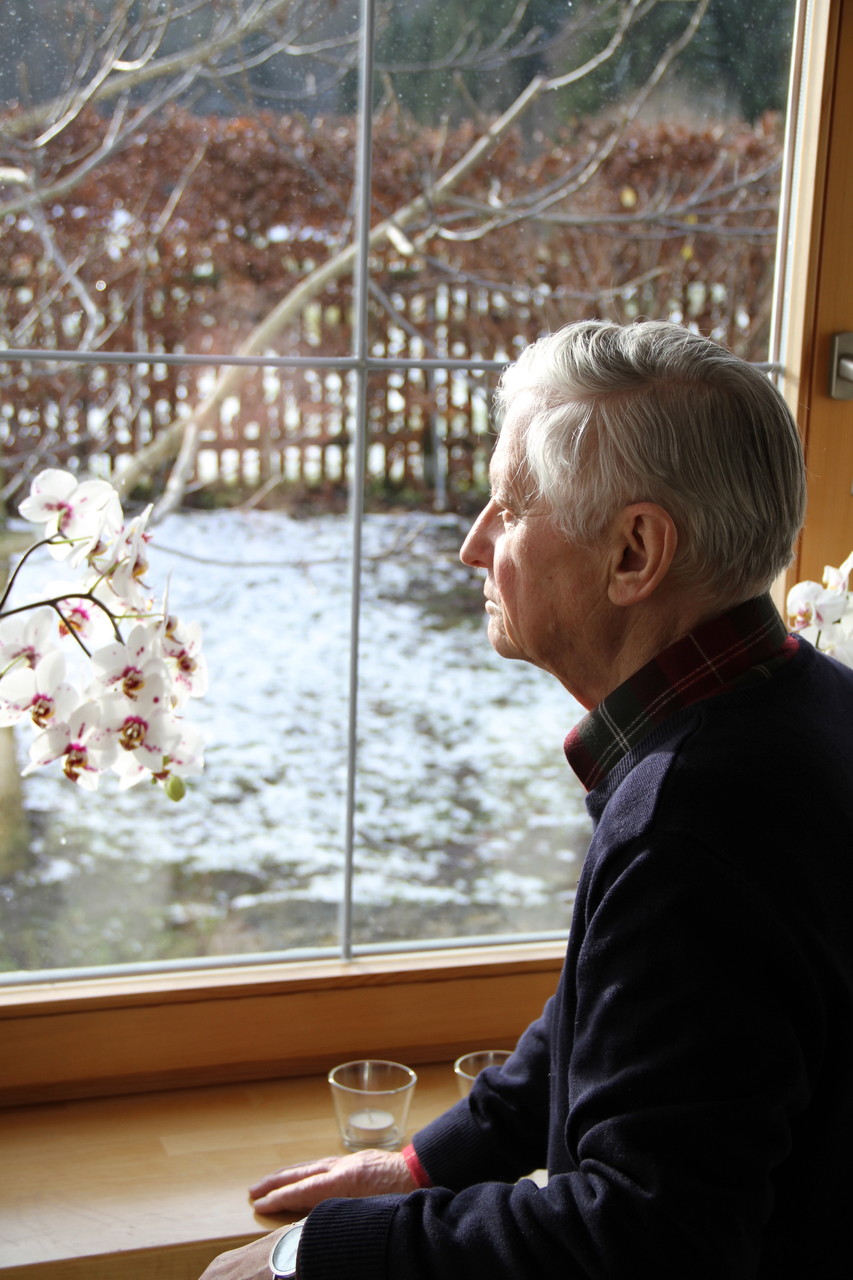 Senior schaut aus dem Fenster